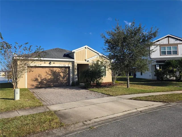a view of a house with a yard and large tree
