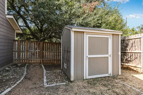 a view of backyard with small cabin and wooden fence