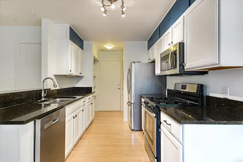 a kitchen with granite countertop a sink a stove and cabinets