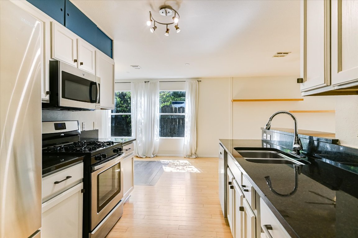 1193 Curve Street Austin, TX 78702 - Photo 7 of 18 a kitchen with granite countertop a sink stainless steel appliances and cabinets