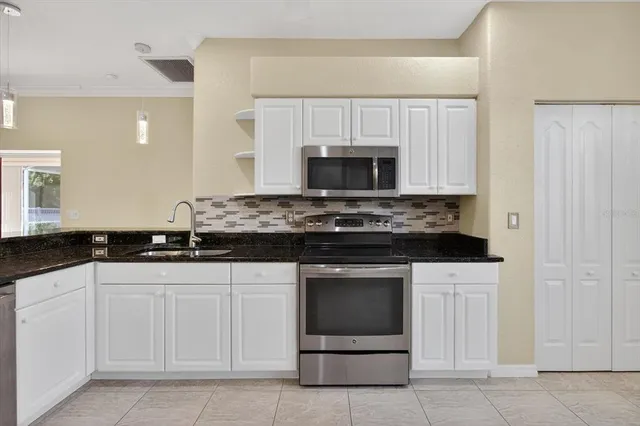an empty room with wooden floor cabinet and windows