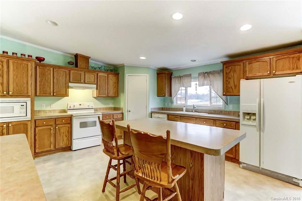 4737 White Store Road Wingate, NC 28174 - Photo 9 of 36 a kitchen with granite countertop a table chairs microwave and refrigerator
