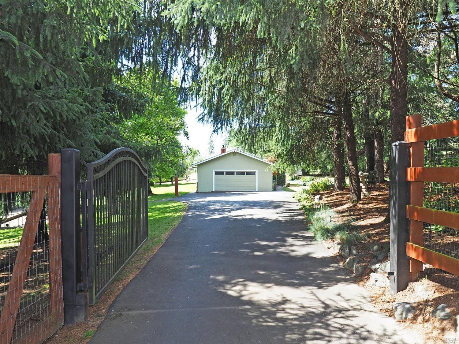 Your own magnificent private, gated and fenced country estate.  On 1+/- acre, this flat, useable land brims with the beautiful bounty of nature in flowers, trees and blooming bushes. Lots of extra parking seen here and more in the back.  Perfectly situated on the land to enjoy lots of sun.  Come on in and explore...