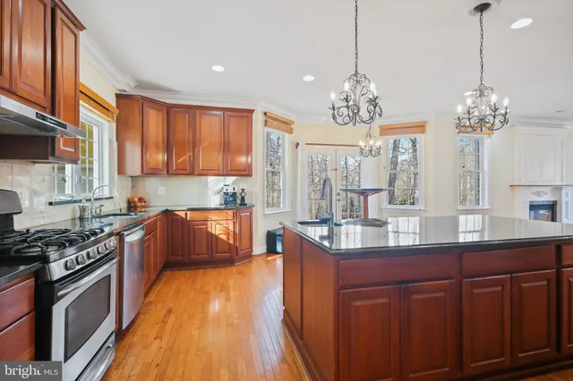 a kitchen with stainless steel appliances kitchen island granite countertop wooden floors and a view of living room