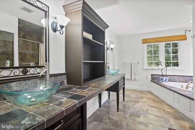 a en suite bathroom with a granite countertop tub and a large window