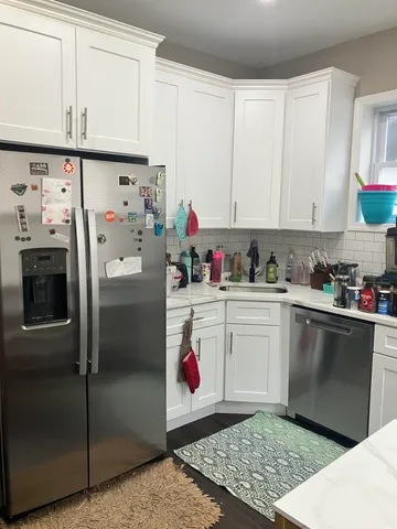 a kitchen with a refrigerator and white cabinets
