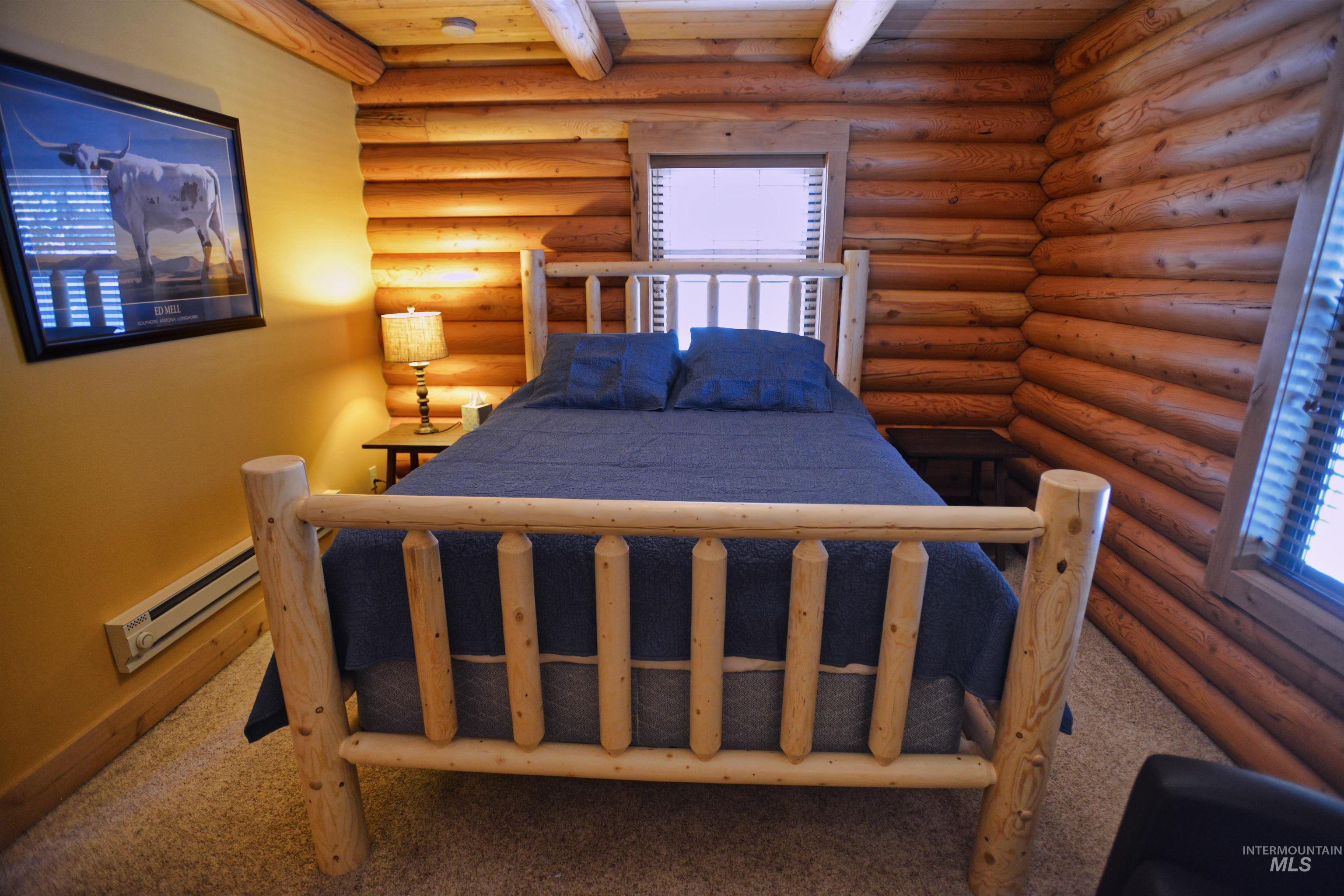 788 Chad Loop McCall, ID 83638 - Photo 16 of 22 Log cabin interior featuring natural wood log walls, exposed wood ceiling beams, wood-framed windows with blinds, and beige carpeting