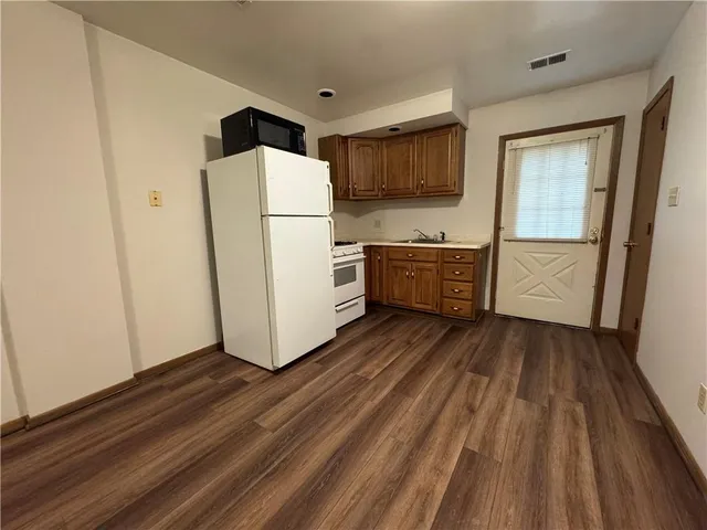 a kitchen with a refrigerator a stove top oven and wooden floor