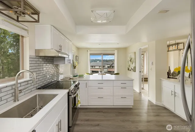 a kitchen with white cabinets and wooden floor
