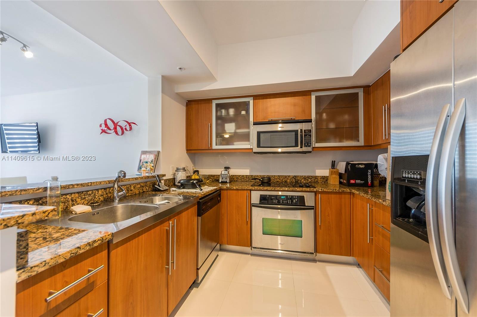 888 Douglas Road, Unit 1407 Coral Gables, FL 33134 - Photo 5 of 11 a kitchen with stainless steel appliances granite countertop a sink stove microwave and refrigerator