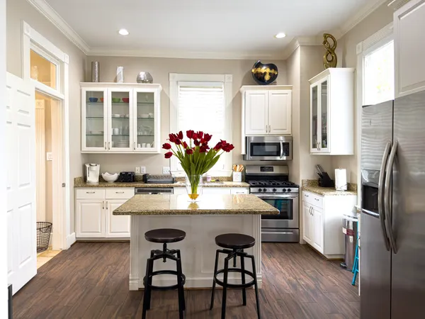 a kitchen with stainless steel appliances granite countertop a dining table chairs refrigerator and sink