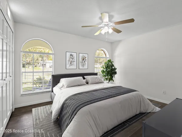 an empty room with wooden floor chandelier fan and windows