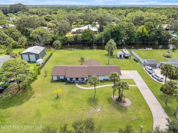 a swimming pool with lawn chairs and large trees