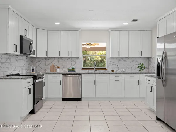 a kitchen with granite countertop white cabinets and a window