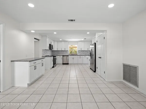a kitchen with a sink a stove a refrigerator and white cabinets