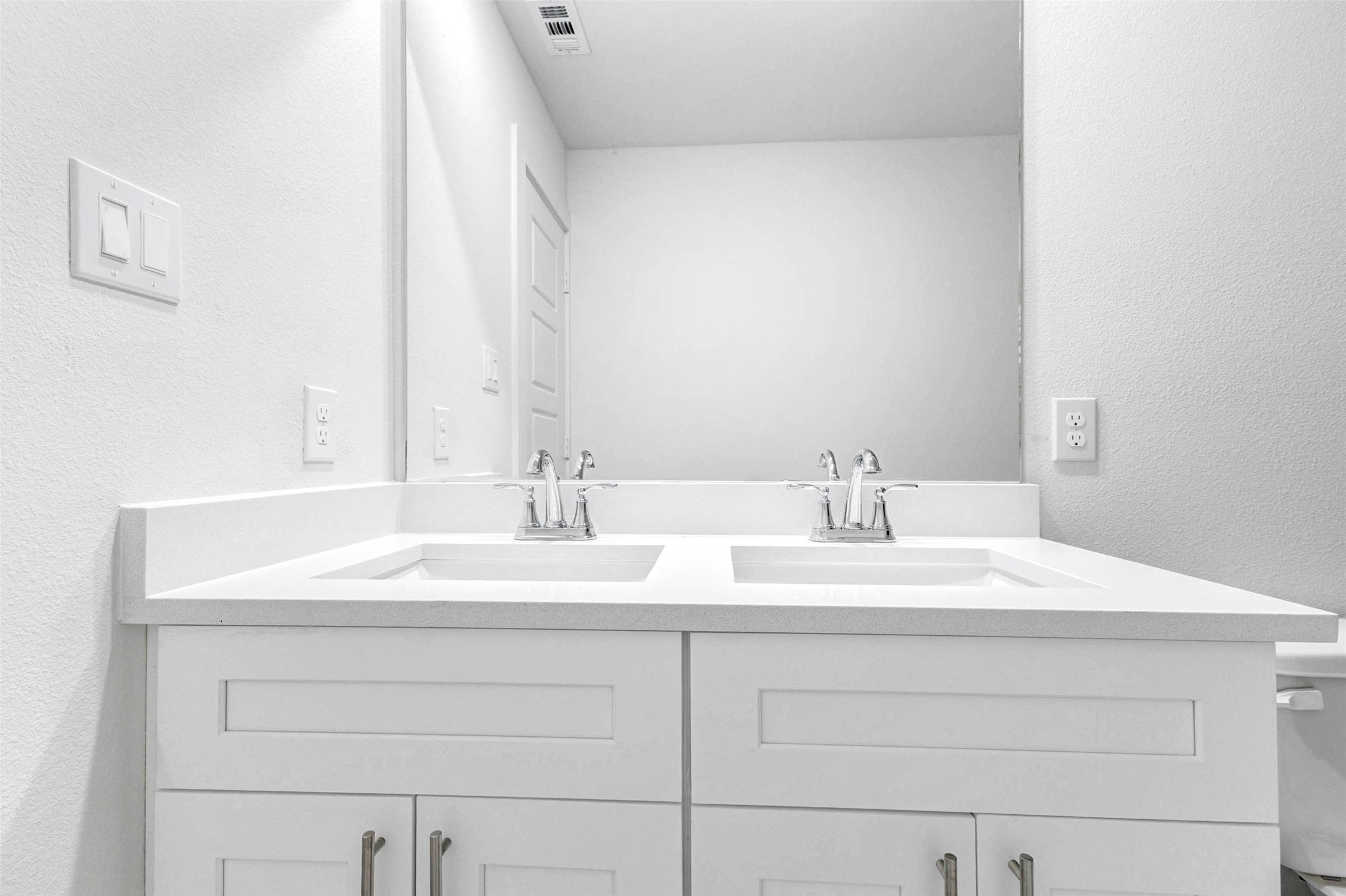 6463 Escondido Drive Rosharon, TX 77583 - Photo 15 of 30 Close-up view of the secondary bath vanity with dual undermount sinks, white cabinetry, chrome fixtures, and a wide mirror. The bright neutral design provides a clean and functional space with plenty of counter area for shared daily routines.