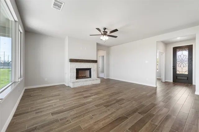an empty room with wooden floor a ceiling fan and windows