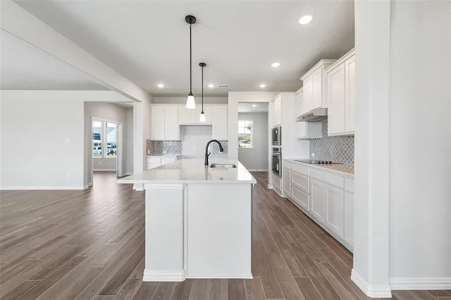 a large kitchen with kitchen island a stove a sink a refrigerator and a wooden floor