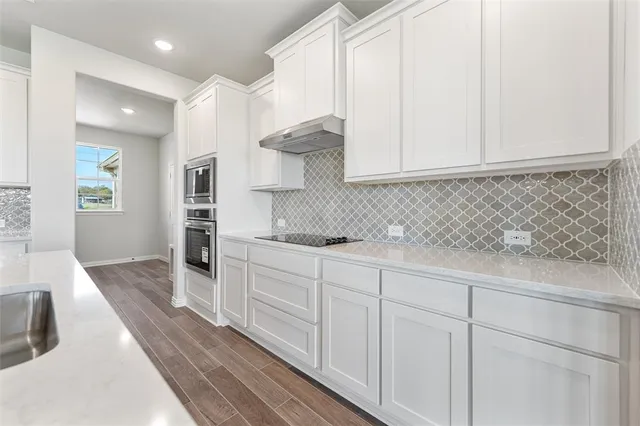 a kitchen with granite countertop white cabinets and sink