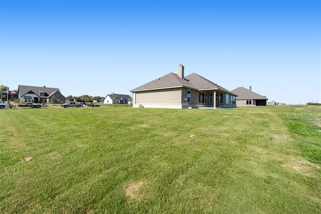 a front view of a house with a garden and lake view