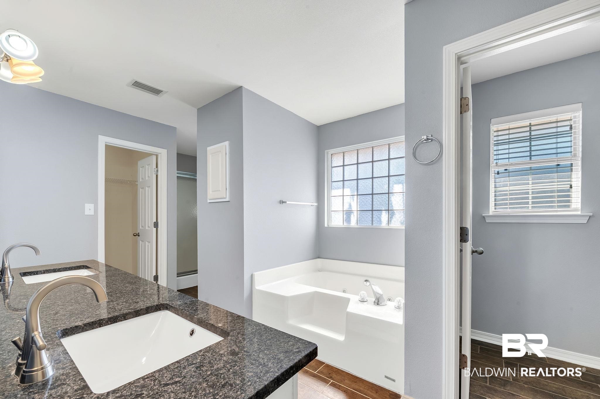 16444 Hamlet Lane Foley, AL 36535 - Photo 28 of 49 Bathroom with visible vents, a sink, a garden tub, and wood tiled floor