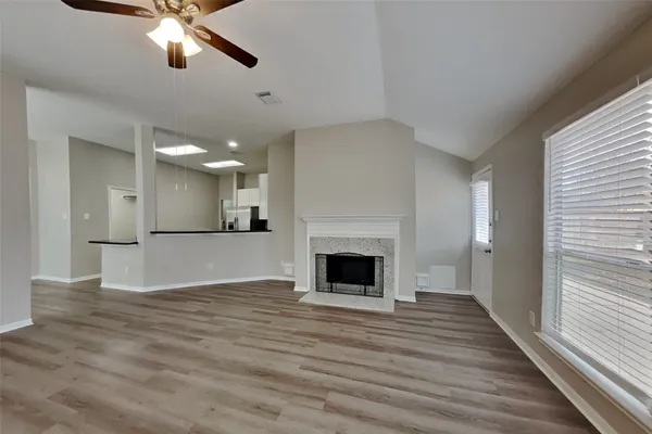 a view of a livingroom with a fireplace a ceiling fan and windows