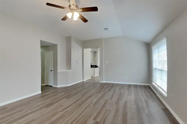 a view of empty room with wooden floor and fan