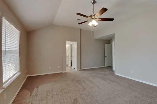 an empty room with chandelier fan and windows