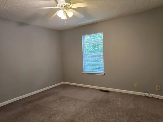 an empty room with a window and a fan