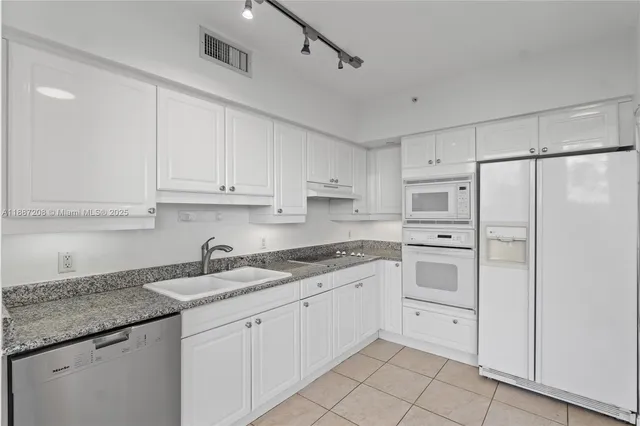 a view of a kitchen with white cabinets and refrigerator