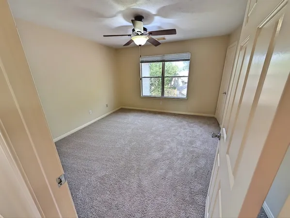 an empty room with windows and fan