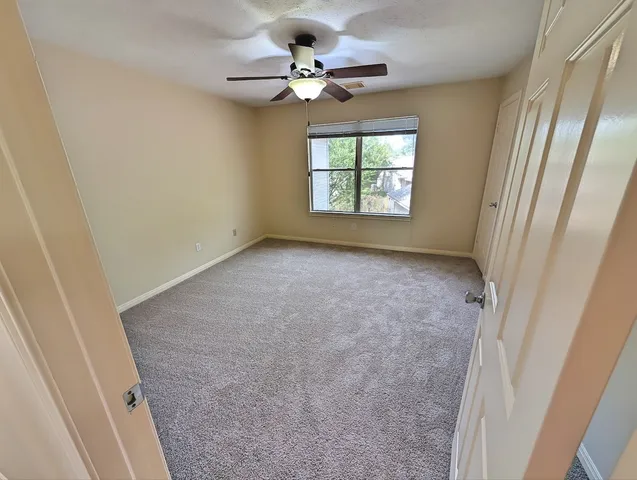 an empty room with windows and fan