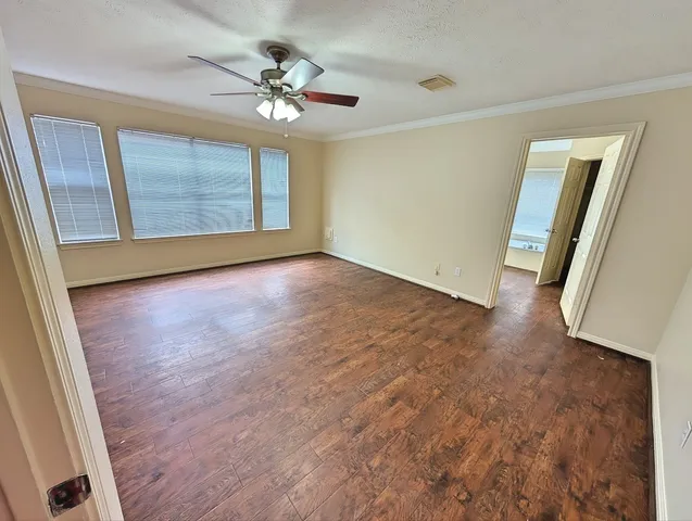 a view of an empty room with a window and wooden floor