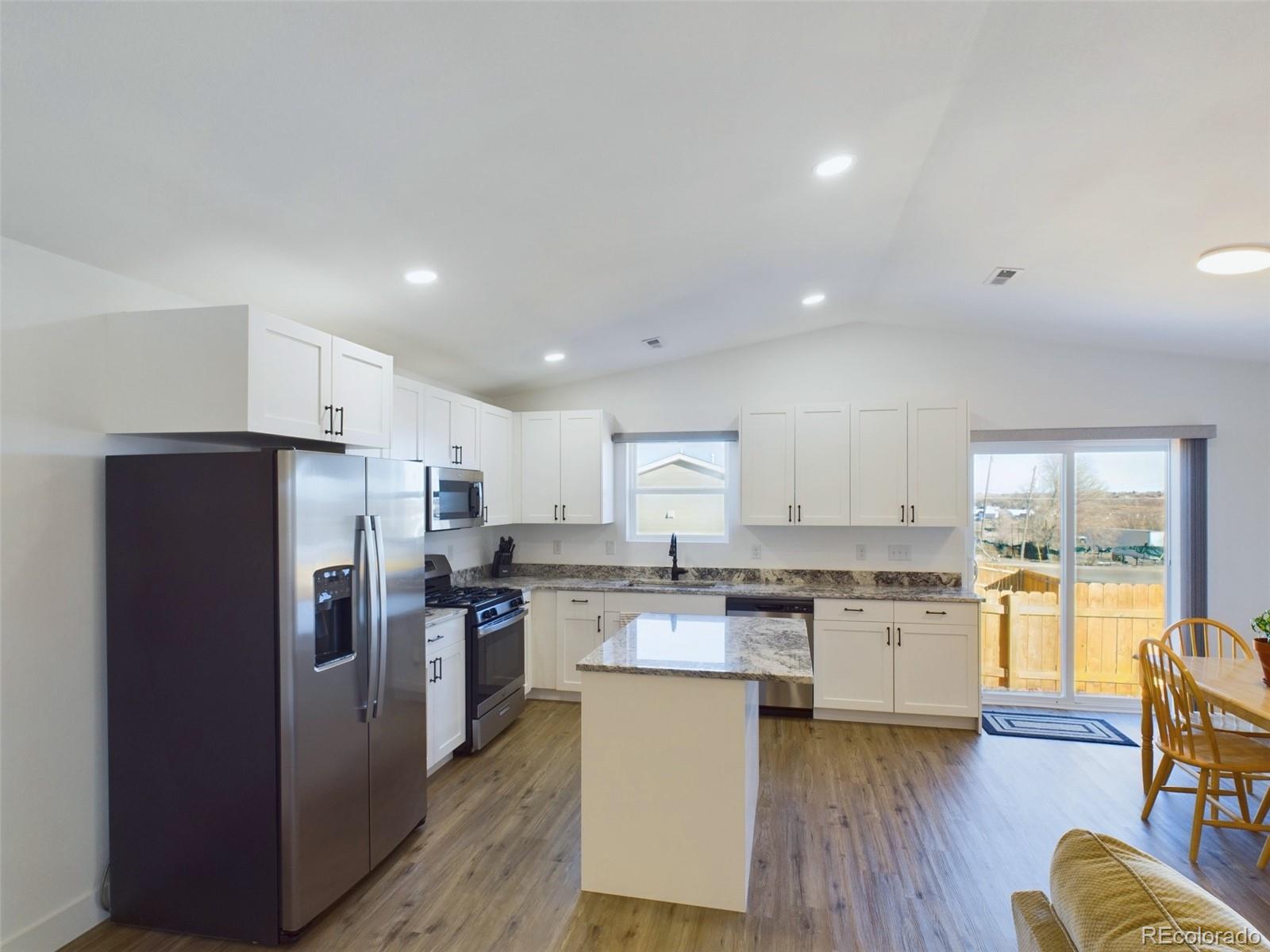 1439 Brewery Road Pueblo, CO 81001 - Photo 3 of 25 a kitchen with stainless steel appliances granite countertop a refrigerator a stove top oven a sink dishwasher and white cabinets with wooden floor