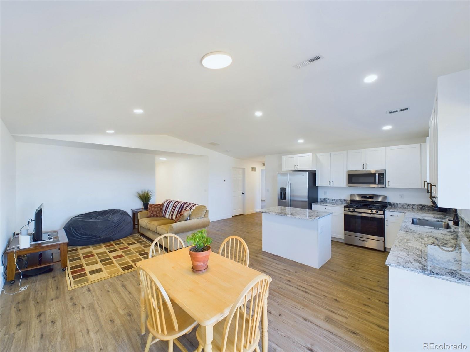 1439 Brewery Road Pueblo, CO 81001 - Photo 6 of 25 a kitchen with stainless steel appliances granite countertop a stove top oven a dining table and chairs with wooden floor