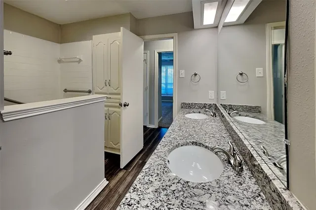 a bathroom with a granite countertop sink a mirror and shower