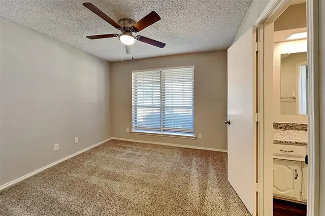 an empty room with windows and a ceiling fan