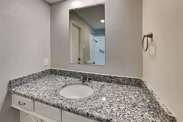 a bathroom with a granite countertop sink and a mirror