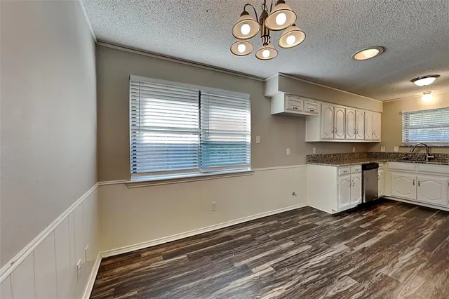 a kitchen with cabinets wooden floor and a window