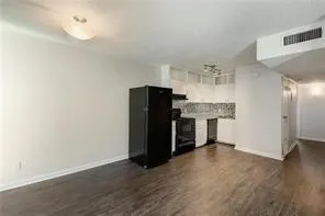 an empty room with a chandelier fan and wooden floor