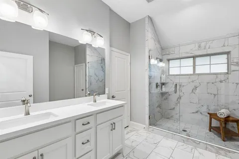 a bathroom with double sink shower and a mirror