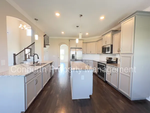a large kitchen with stainless steel appliances lots of counter space and wooden floor