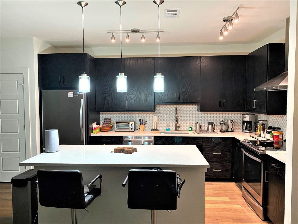 1615 East 7th Street, Unit 304 Austin, TX 78702 - Photo 4 of 12 a kitchen with a sink a stove and cabinets