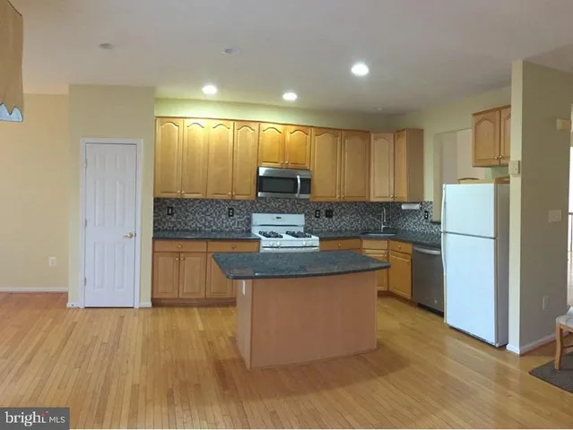 a kitchen with kitchen island a counter top space a sink a refrigerator and a stove