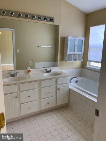 a bathroom with a tub sink and mirror