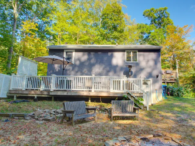 a view of a house with a wooden deck and furniture