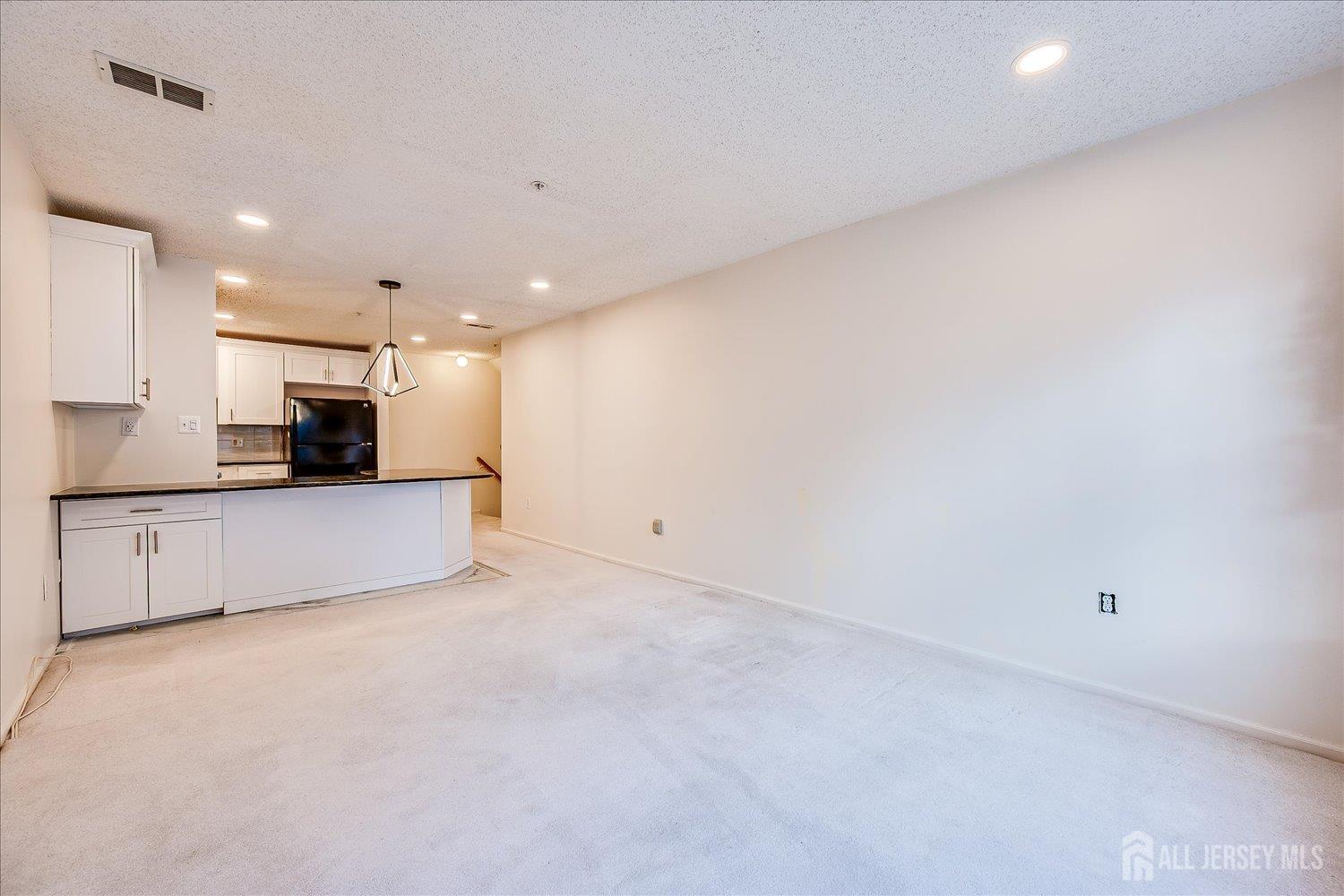 10 Guisborough Way Edison, NJ 08820 - Photo 11 of 27 an empty room with kitchen view and a fireplace