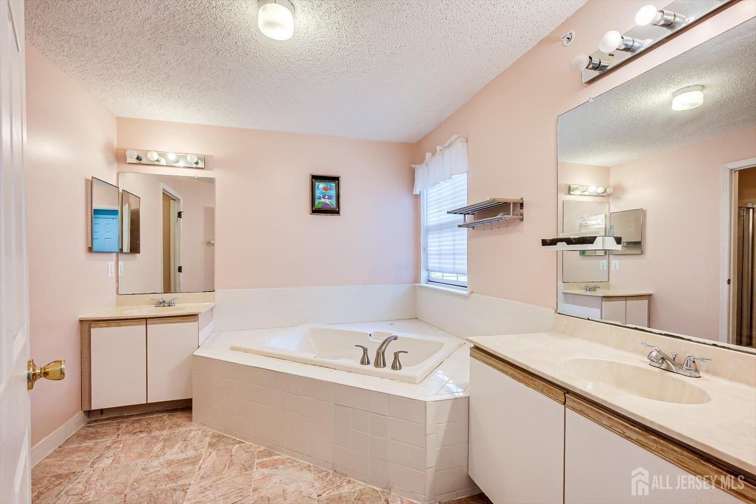 10 Guisborough Way Edison, NJ 08820 - Photo 19 of 27 a bathroom with a tub sink and mirror