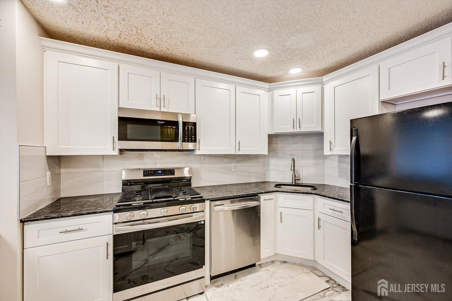 10 Guisborough Way Edison, NJ 08820 - Photo 7 of 27 a kitchen with white cabinets stainless steel appliances and sink