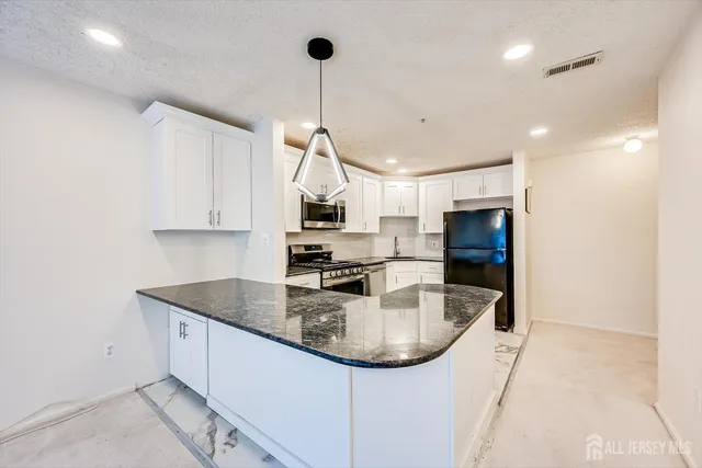 a kitchen with stainless steel appliances granite countertop a sink a stove and a refrigerator